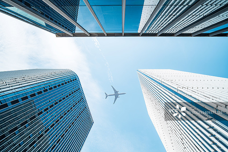 低角度仰拍飞机飞过写字楼图片素材