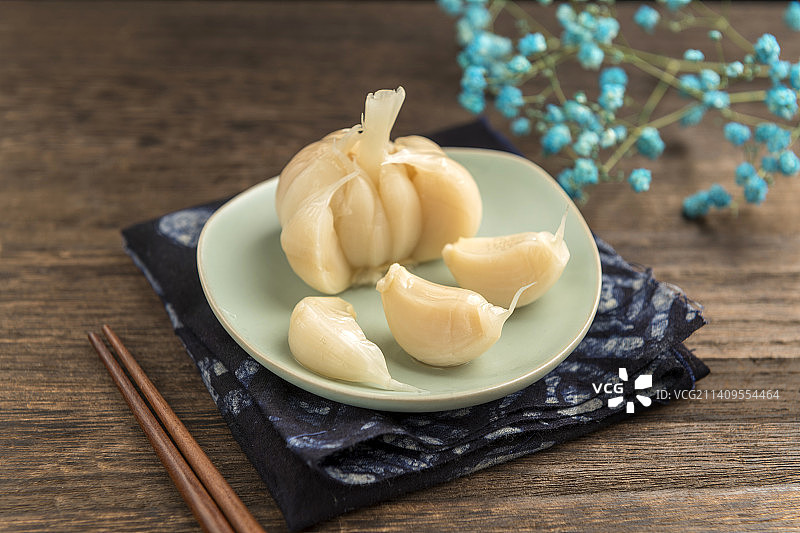 一盘糖蒜摆放在木桌面上特写图片素材