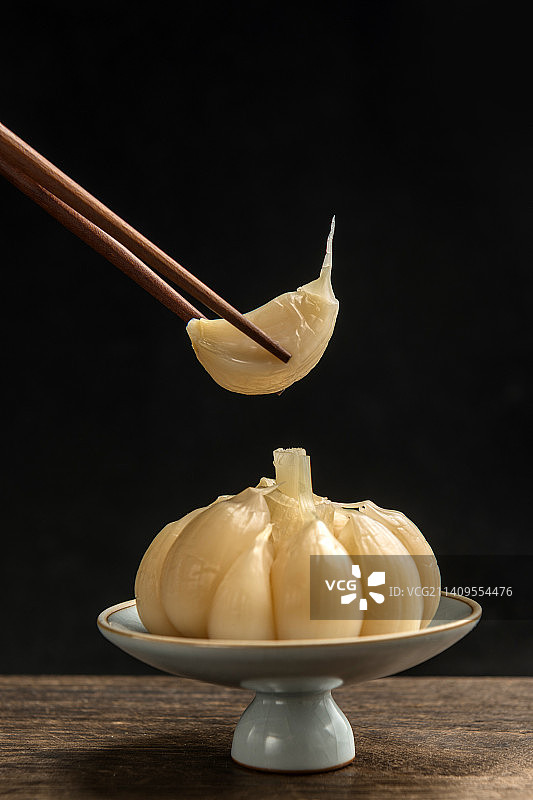 一盘糖蒜摆放在木桌面上特写图片素材