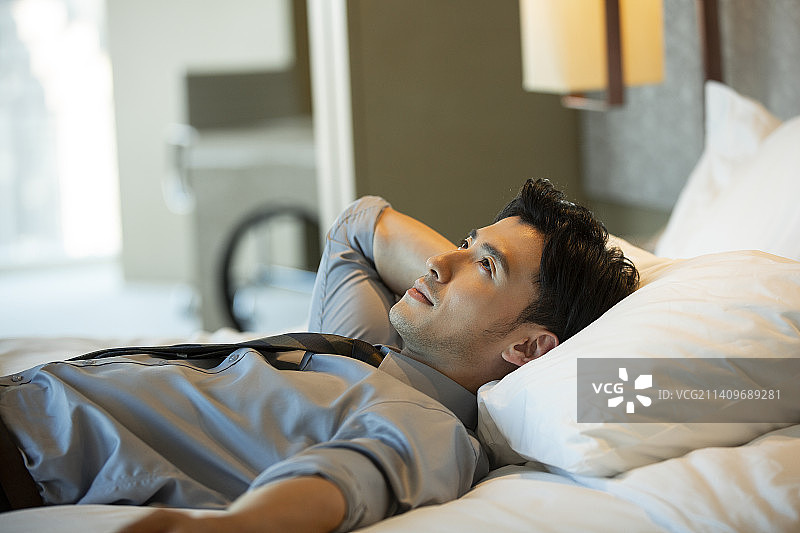 成熟的商务男子躺在酒店房间床上休息图片素材
