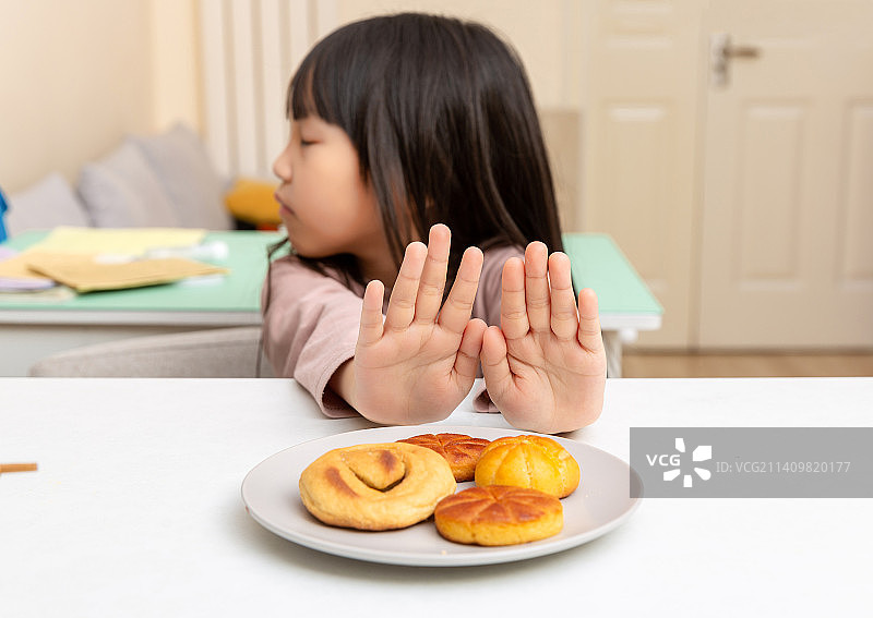 室内白色餐桌前不想吃饭的小女孩图片素材