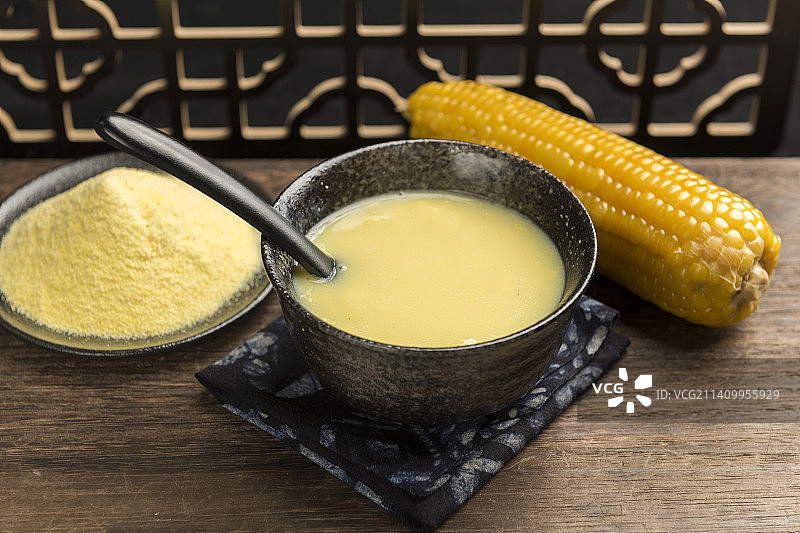 一碗玉米糊与玉米面玉米摆放在木桌面上特写图片素材