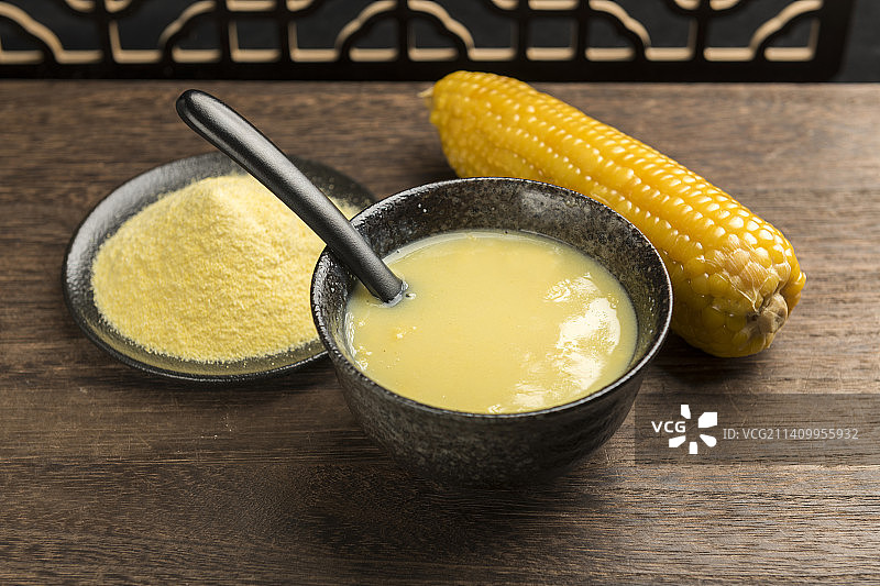 一碗玉米糊与玉米面玉米摆放在木桌面上特写图片素材