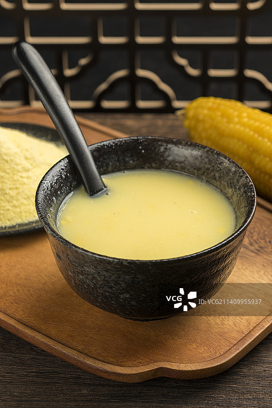一碗玉米糊与玉米面玉米摆放在木桌面上特写图片素材