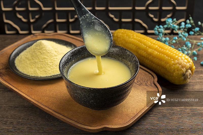 一碗玉米糊与玉米面玉米摆放在木桌面上特写图片素材
