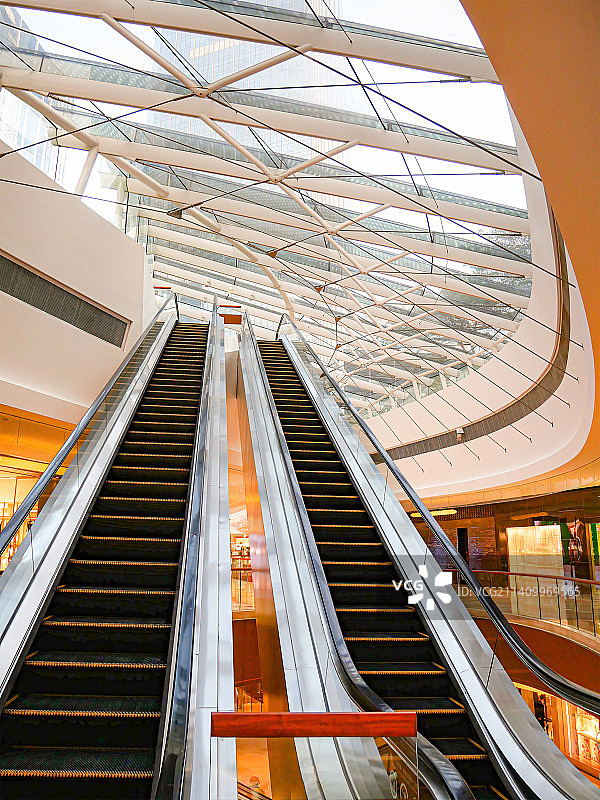高端商务区配套商场内的巨型玻璃天幕穹顶透出阳光双向自动手扶电梯直通顶楼高雅别致时尚充满高级感图片素材