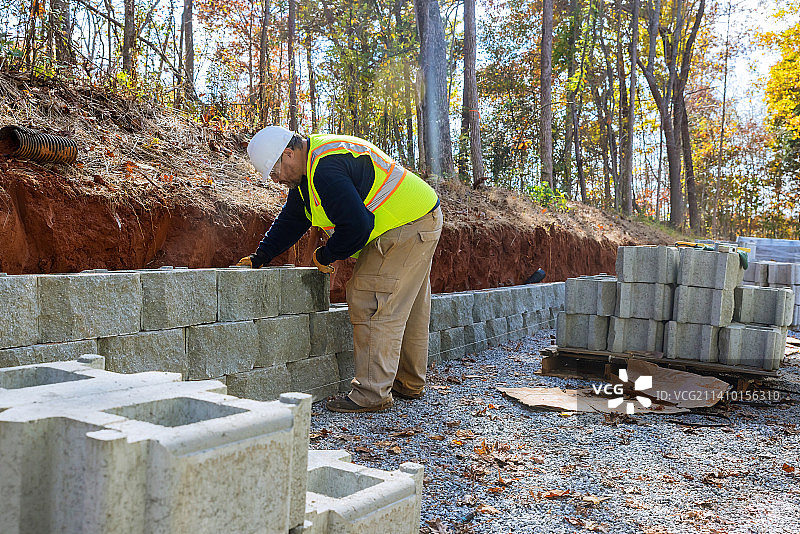 一名男子在新建的工地上找平混凝土砌块墙图片素材