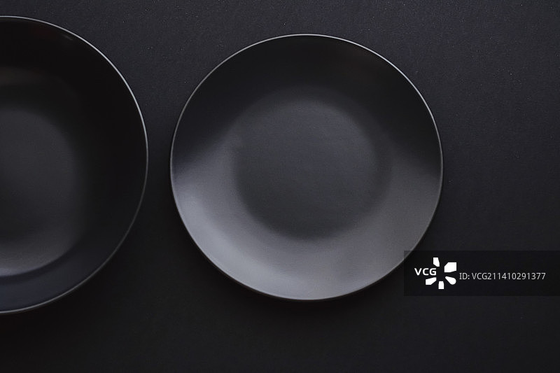 黑色背景上的空盘子，节日晚餐的高级餐具图片素材