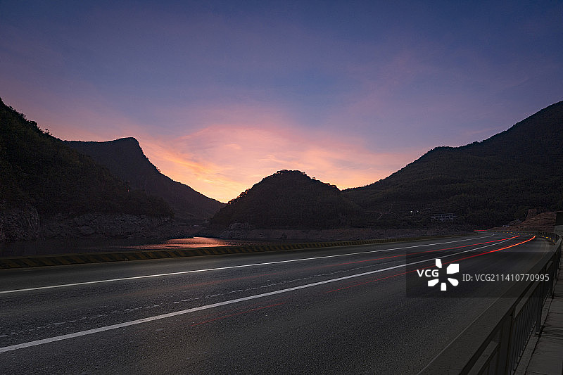 黄昏山区水库旁的一条柏油路图片素材