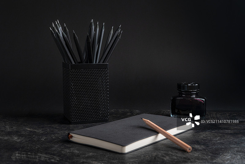 黑色的铅笔本子放在暗调的背景中静物照图片素材