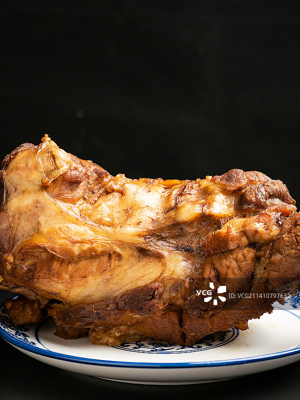 黑色背景的酱卤猪筒子骨美食小吃图片素材
