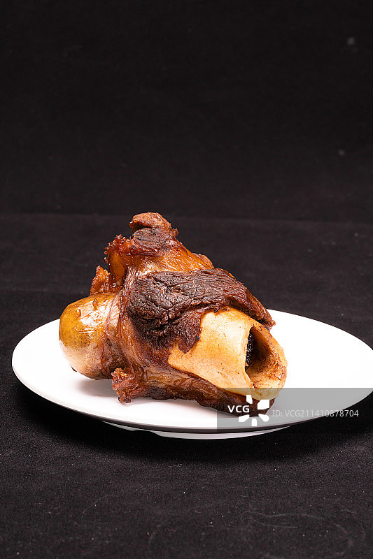 黑色背景的酱卤猪筒子骨，餐饮美食，卤猪棒骨图片素材