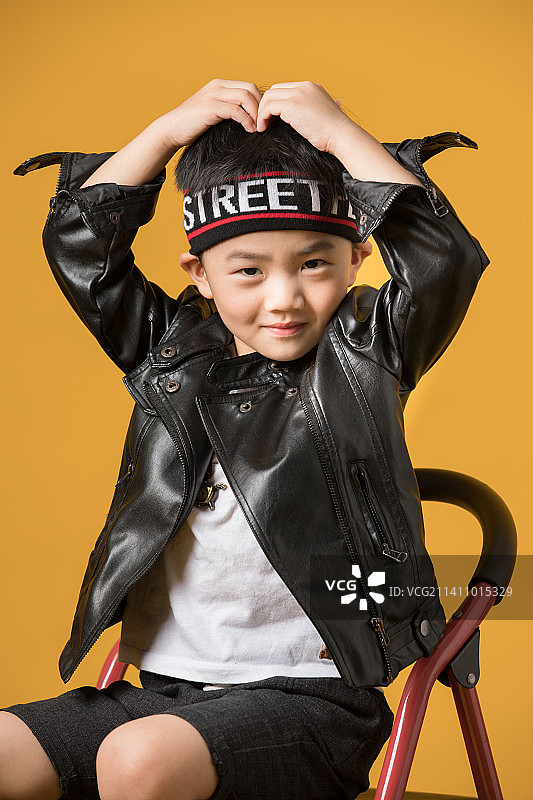 橙色背景下穿皮衣的帅气中国小男孩图片素材