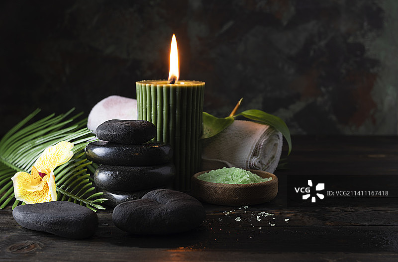 玄武岩按摩和香薰蜡烛在黑暗的桌子上图片素材