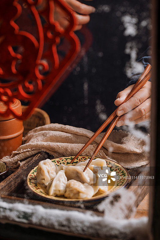 中国节下雪的冬天在木窗边夹饺子图片素材