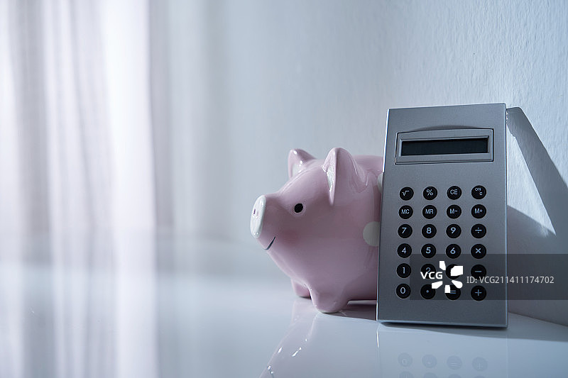 马来西亚，晨光洒在存钱罐和计算器上图片素材