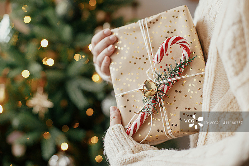 圣诞节：手持时尚礼品盒，背景是点缀着彩灯的圣诞树，利沃夫，利沃夫州，乌克兰图片素材