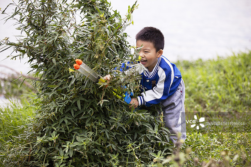 小男孩在湖边玩水枪图片素材