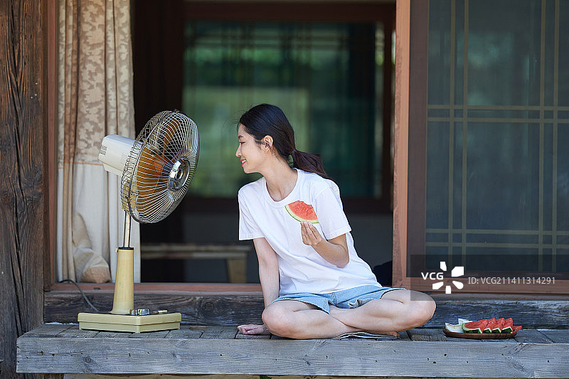 夏日假期：女性的休闲周末，地板、电风扇和西瓜图片素材