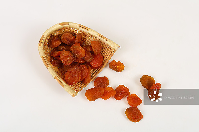 簸箕里的果脯杏肉散落在白色背景上图片素材