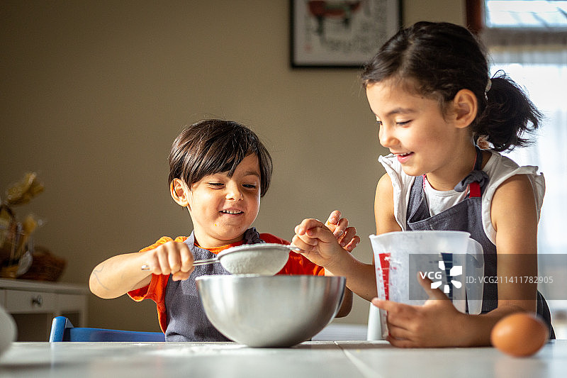 两个快乐的女孩穿着灰色围裙烤饼干图片素材
