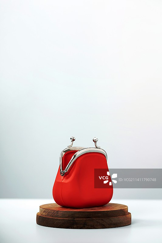 蓝色背景木制讲台上的红色敞口零钱包图片素材