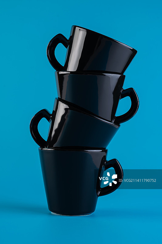 蓝色背景上的黑色杯子塔，极简主义图片素材