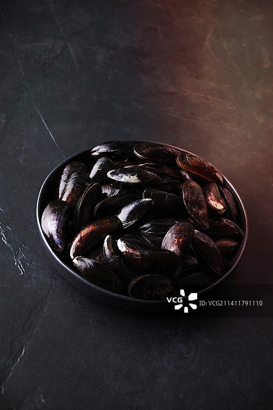 深色背景上的新鲜生贻贝碗图片素材