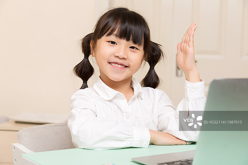 身穿白色衬衣在家上网课举手的小女孩图片素材
