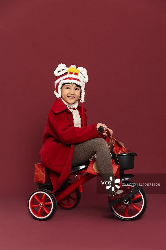 儿童庆祝春节系列：小女孩骑着小三轮车运送春节礼物图片素材