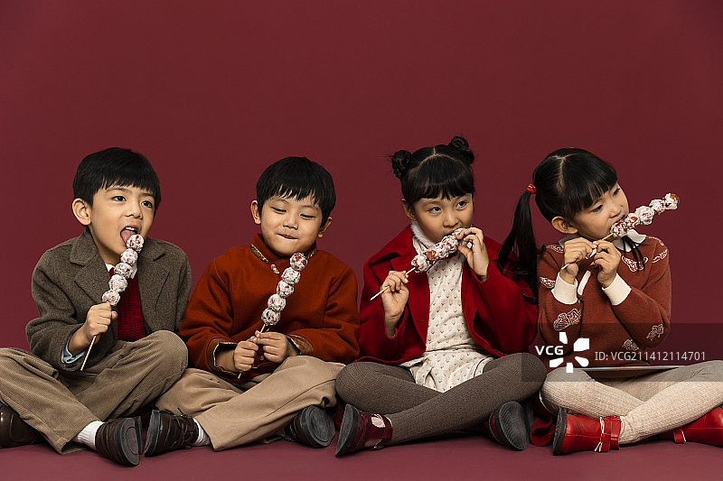 儿童庆祝春节系列：欢乐的小男孩和小女孩们吃糖葫芦庆祝新春图片素材