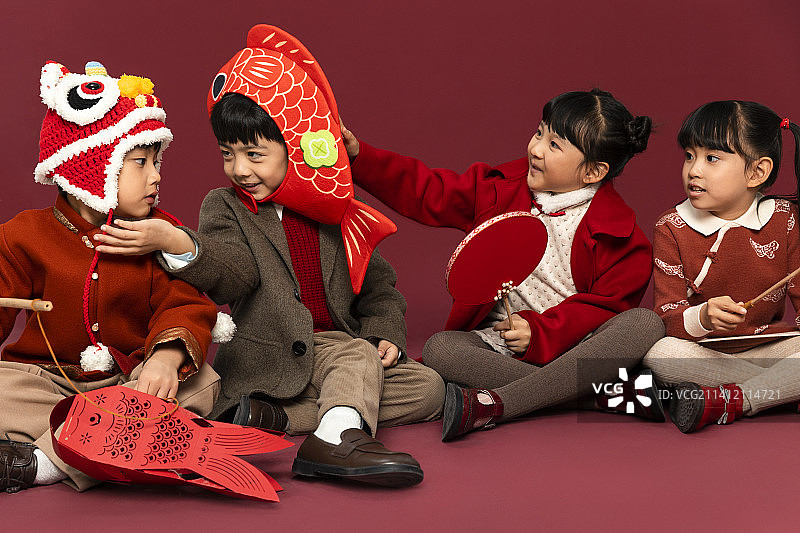 儿童庆祝春节系列：可爱的儿童们拿着灯笼、扇子、戴着鲤鱼头套打闹图片素材