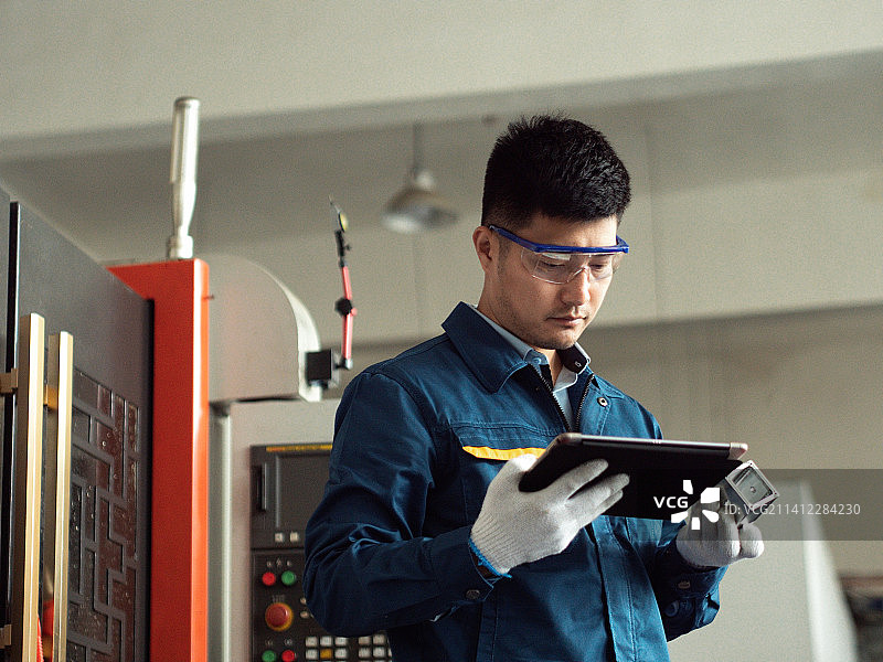 男性工人在工厂车间数控机床工作图片素材