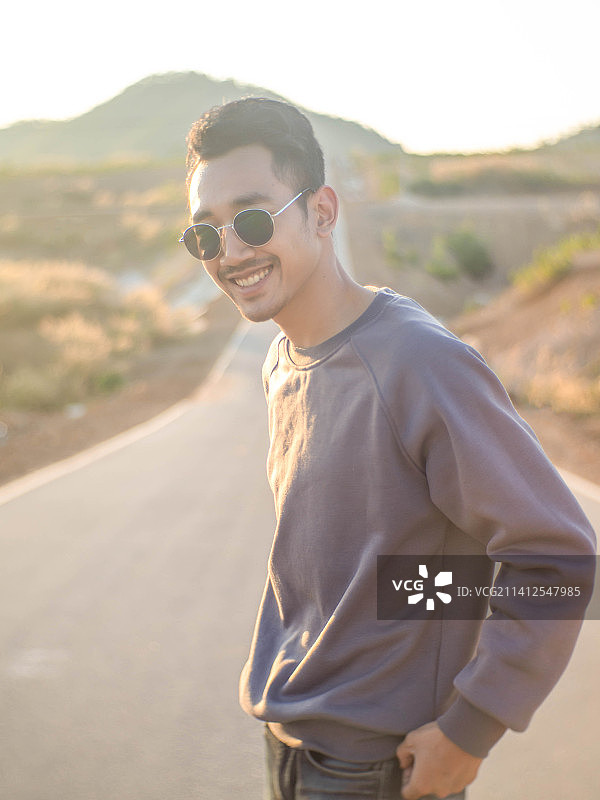 一名男子背着背包站在泰国的道路中央图片素材