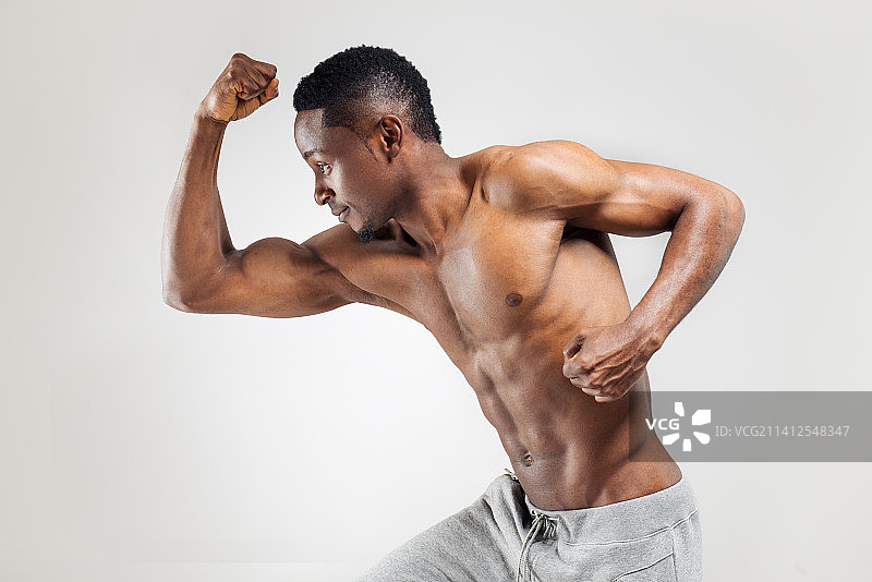 健壮的年轻男人在白色背景下展示肌肉图片素材