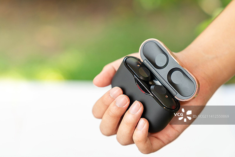 手持黑色真无线耳机和充电盒，泰国图片素材