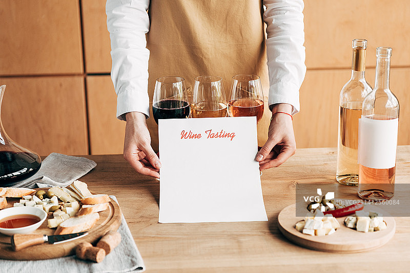 男子手持酒瓶的腰部特写，桌上有文字图片素材
