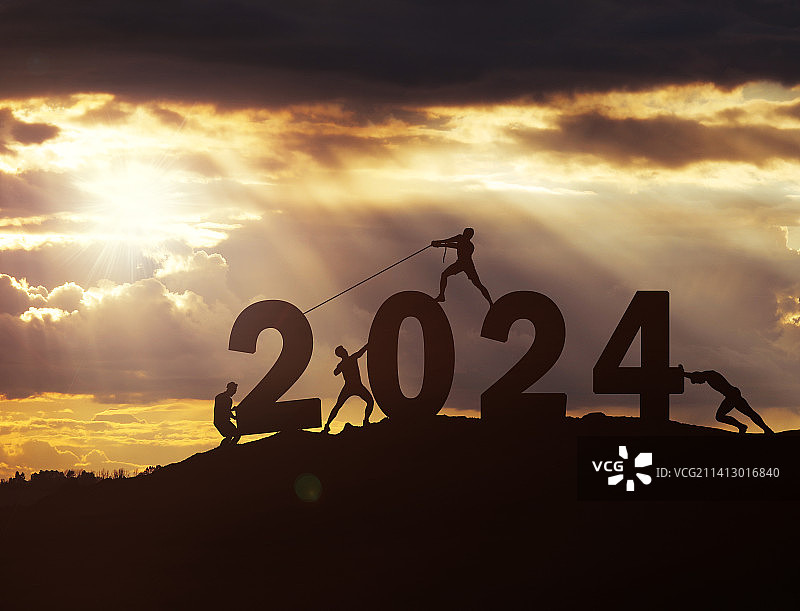 一群青年人将2024拖拽上山顶剪影图片素材