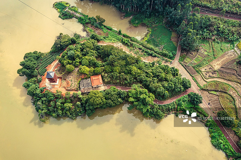 航拍水边的绿岛，树林掩映着寺庙。图片素材
