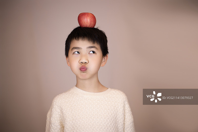 一个帅气的中国小男孩头顶着苹果图片素材