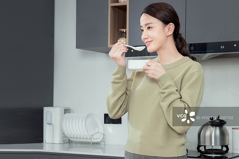 在厨房吃早餐的年轻女人图片素材