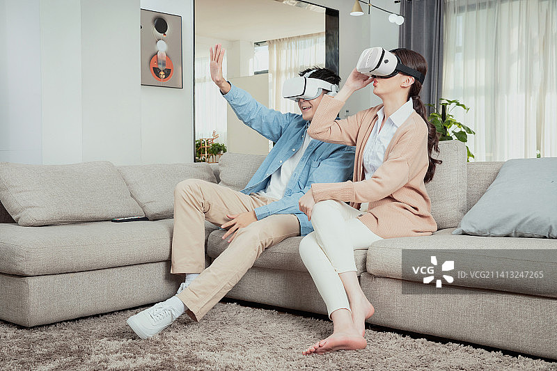 坐在沙发上使用VR娱乐的青年情侣图片素材