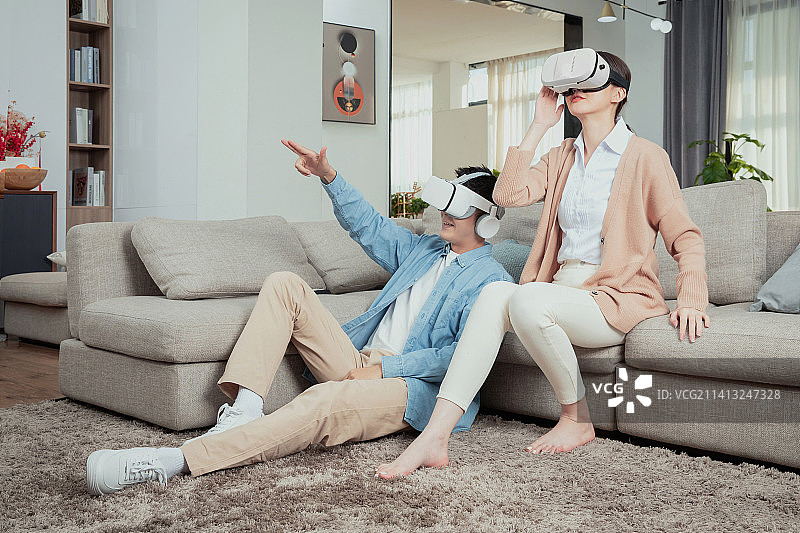 坐在沙发上使用VR娱乐的青年情侣图片素材