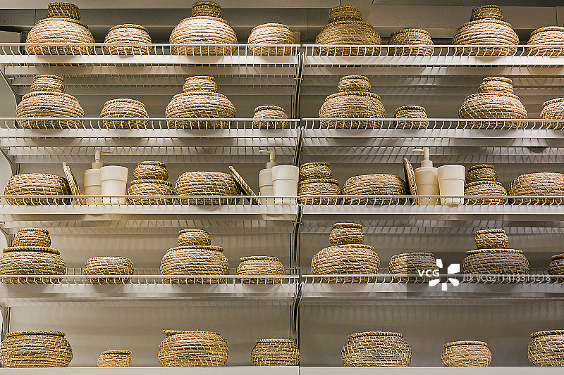 白色货架上整齐排列几排圆形草编工艺收纳筐图片素材
