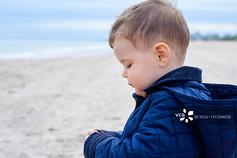 可爱的男婴在寒冷的一天于美国纽约的海滩上玩耍图片素材