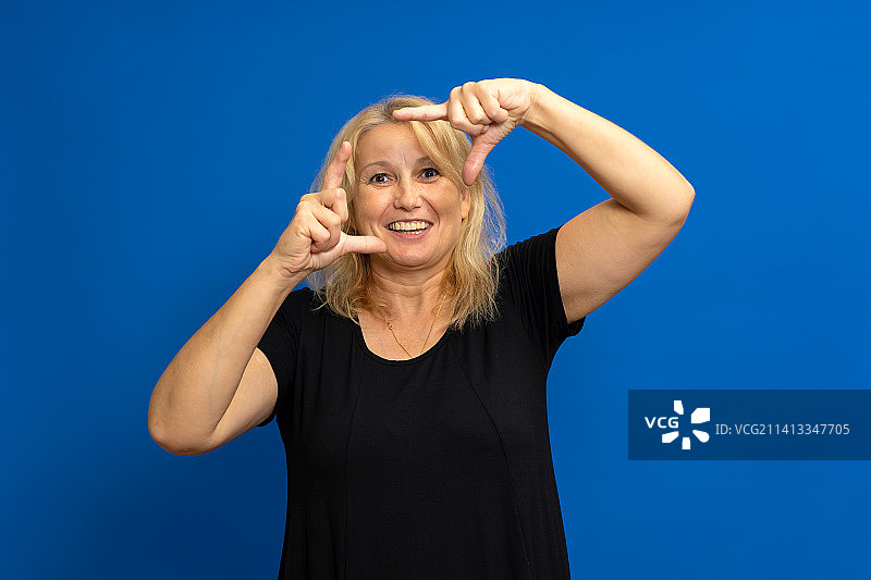 用手指做框架的快乐白人金发女性，隔离于图片素材