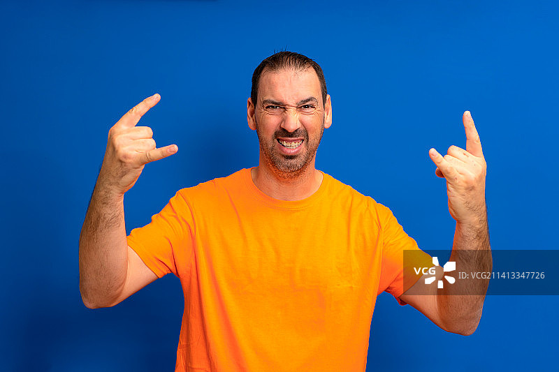 留着胡子的拉丁裔男人穿着橙色T恤，表情夸张图片素材