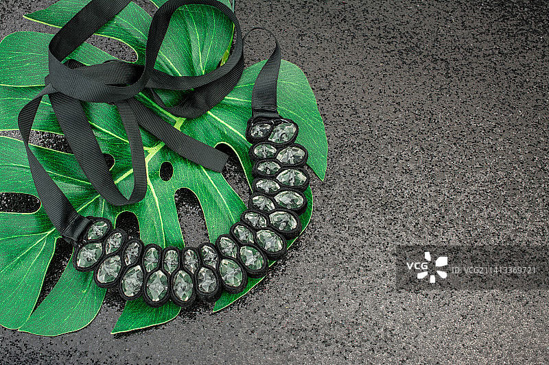 带有绿色树叶和项链的黑色背景，英国图片素材