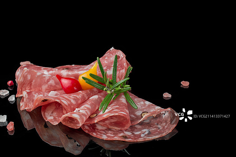 黑色背景上的帕尔马火腿、意大利熏火腿和萨拉米香肠片图片素材