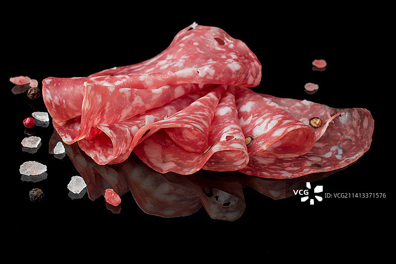 黑色背景上的帕尔马火腿、意大利熏火腿和萨拉米香肠片图片素材
